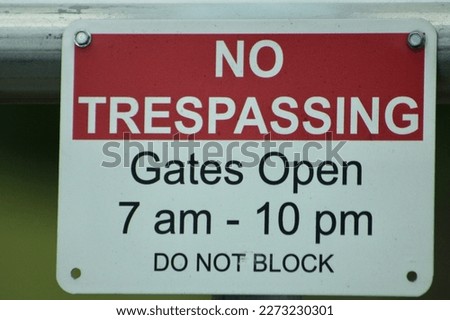 A sign that says "no trespassing gates open 7 am to 10 pm do not block".