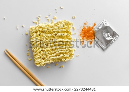 Instant noodles with seasonings on the table.  Uncooked noodles with red chilli powder.  Flat lay top view food photography.  Food from above concept. Royalty-Free Stock Photo #2273244431