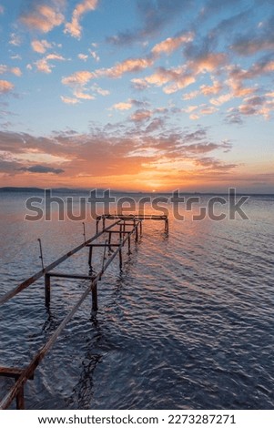 Iron made pier on sunset with beautiful colorful clouds and silky smooth sea water with long exposure photography technic