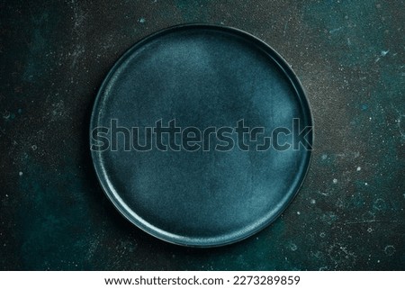 Round blue dinner plate. On a dark green-turquoise background. Free space for text.
