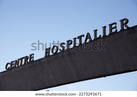 Signage: three-dimensional letters mounted on a concrete structure over the entrance to a French hospital.