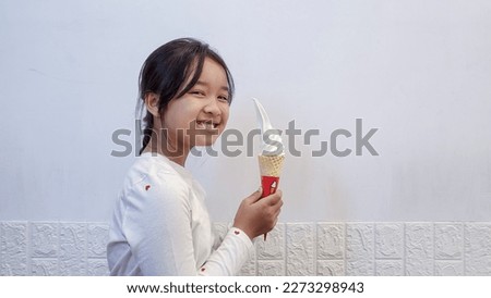 Cute girl with gray eyes looking away and licking sweet ice cream in the cafe.