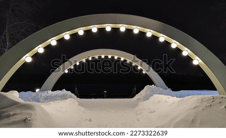Arch with white lanterns on city street on a dark winter night and white snow drifts. Background for photo shoot