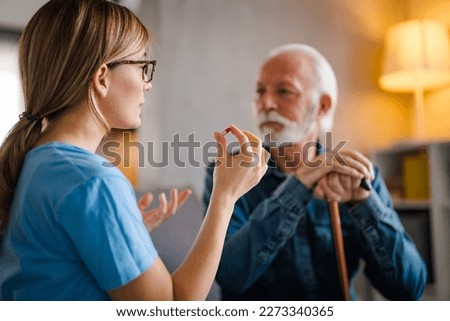 Nurse Helping Senior Man To Organize Medication On Home Visit. Nurse giving senior man prescription drugs. Senior male patient consult with physician nurse at nursing home.