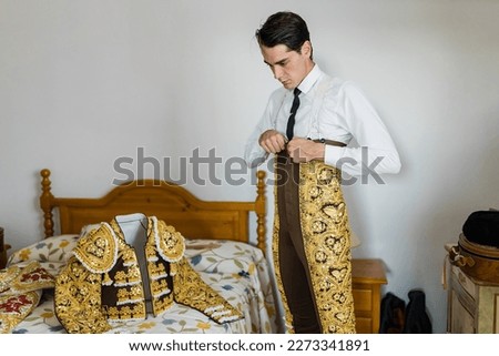 Young bullfighter in bedroom dressing up the lights suit before a bullfight Royalty-Free Stock Photo #2273341891