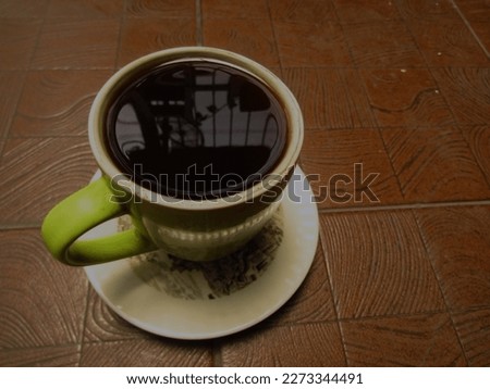 A Cup of High Quality Espresso Black Bitter Coffee Hot Smoky Morning Photographed Close Up From Above. Coffee in a Green Cup on a Brown Ceramic Floor in a Nature Patterned Cafe. Isolated Low Key Mood