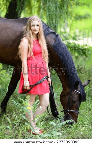 outdoor portrait of young beautiful woman with horse. Against the background of a tree. 
