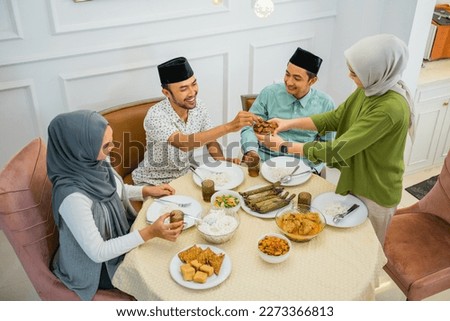 wife serves dates when breaking the fast with friends at the dinner table Royalty-Free Stock Photo #2273366813