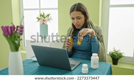Young beautiful hispanic woman using laptop sitting on the table being sick at home