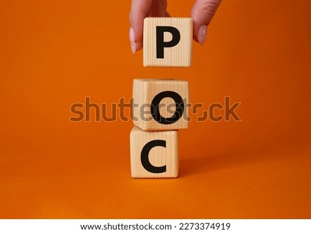 POC - Proof of Concept symbol. Wooden cubes with words POC. Businessman hand. Beautiful orange background. Business and POC concept. Copy space.