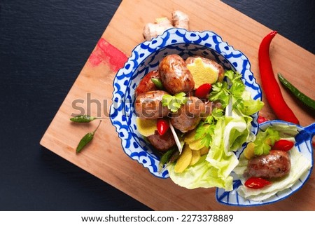 Food concept Sai krok Isan or Isaan Thai-Laos fermented pork and rice sausages in Tradition thai ceramic pedestal plate on black background with copy space Royalty-Free Stock Photo #2273378889