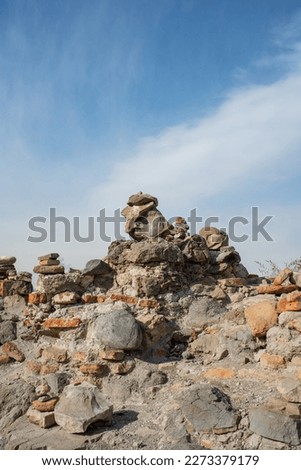 Rock balancing in old mountains of Georgia. Tourists made stone pyramids in sunny day on old fortress wall
