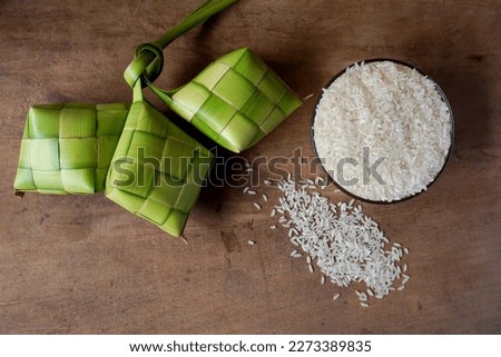 Close up view of Ketupat and rice, an Indonesian traditional cuisine very popular during Hari Raya Idul Fitri. Ketupat is a natural rice casing made from young coconut leaves for cooking rice. Royalty-Free Stock Photo #2273389835