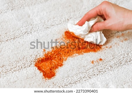 Female's hand soaks up excess food on a white carpet indoors. Cleaning. closeup. daily life stain concept. High quality photo
