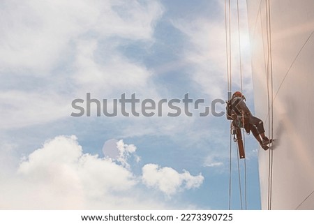 Closeup male worker inspected tank whites wearing safety first harness rope safety line working at a high tank shell plate sunlight. Royalty-Free Stock Photo #2273390725