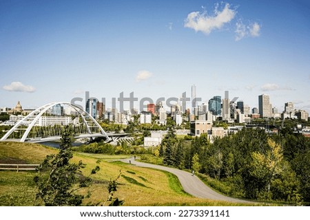 View of the Walterdale suspension bridge in Edmonton Alberta Canada during the day with field and bike path in foreground and view of Edmonton skyline Royalty-Free Stock Photo #2273391141