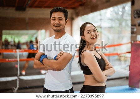 the female boxer and the male boxer standing back to back with hand crossed while standing inside the box ring