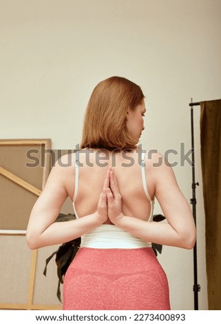 a woman does yoga at home with her hands folded on her back