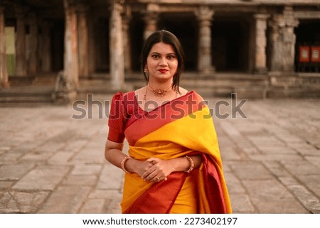 A selective focus of a young Indian woman in saree yellow and red coloured saree at Belur Chennakeshava Temple, Karnataka, India. Royalty-Free Stock Photo #2273402197