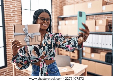African american woman ecommerce business worker make selfie by smartphone holding package at office