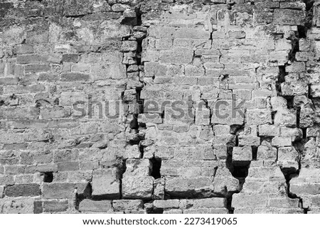 Big deep crack on old wall. Abstract image of numerous cracks, the effects of an earthquake. Black and white photo. Close-up. Copy space. Selective focus.