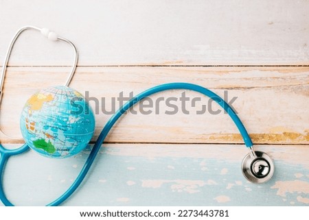 World Health Day. Top view doctor stethoscope wrapped around world globe isolated on wooden background with copy space for text, Save world day, Health care and medical concept
