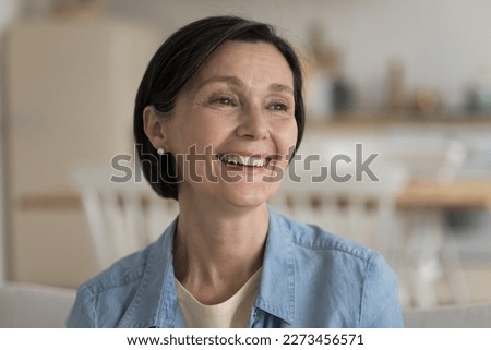 Cheerful positive pretty mature lady candid face portrait. Happy attractive black haired middle aged woman looking away with toothy smile, laughing, having fun. Facial close up
