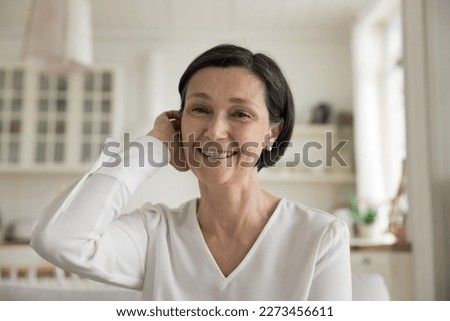 Happy mature brunette lady home screen head shot portrait. Cheerful senior woman talking on video call, looking at camera, smiling, laughing, touching hair, enjoying communication Royalty-Free Stock Photo #2273456611
