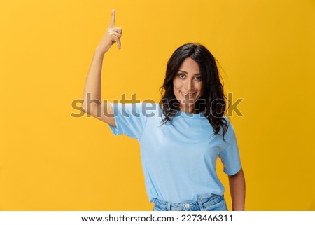 Woman signal smile with teeth emotion portrait in blue t-shirt on yellow background, hands up, surprise, lifestyle, copy space