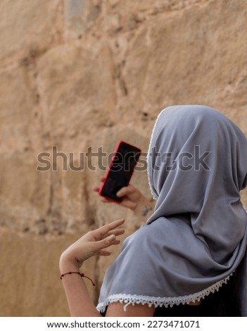 beautiful woman with islamic features, enjoying the day, walking through the streets and taking a picture of herself, woman with hijab
