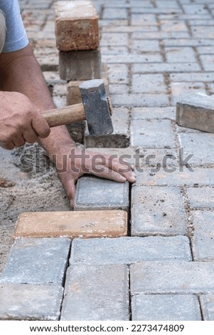 Brazilian and construction worker tapping a small mallet on the concrete block_vertical. Royalty-Free Stock Photo #2273474809
