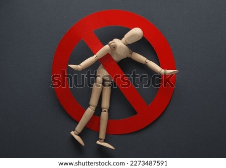 Wooden puppet with a prohibition sign on gray background