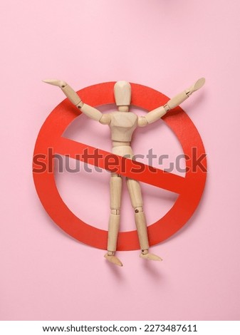 Wooden puppet with a prohibition sign on a pink background