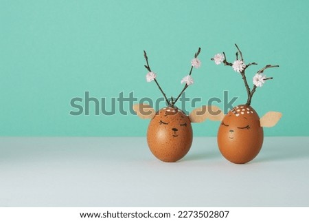Funny deers made of eggs on white and pastel green background. Brown Easter eggs decoration. Space for your text.