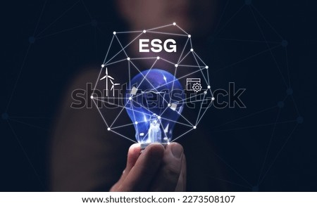 man's hand holding a light bulb on black background .ESG environment social governance investment business concept. ESG icon