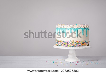 Birthday Cake with a blue ganache drip and colorful sprinkles on a white background