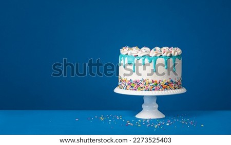 White birthday drip cake with teal ganache over dark blue background Royalty-Free Stock Photo #2273525403