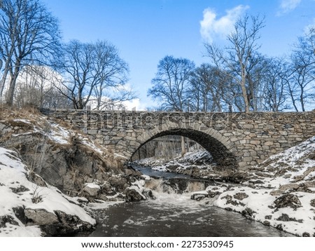 Old stone bridge over a river in winter time