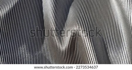Wavy surface of silk fabric with striped black and white print,
with zigzag fold (macro, texture).
