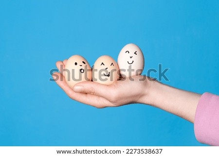 Hand holding three easter eggs with a funny face drawn on it. Easter or healthy diet eating concept.