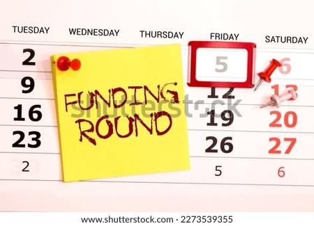 Funding round. Business concept. notepad with spring on gray background near desk clock and money
