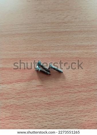 three small screws once used on a wooden table