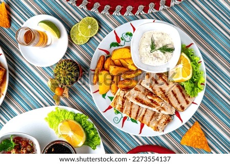 Traditional mexican food. Pike-perch baked with vegetable sauce and potato wedges. Colorful Food Table Celebration Delicious Party Meal Concept. 