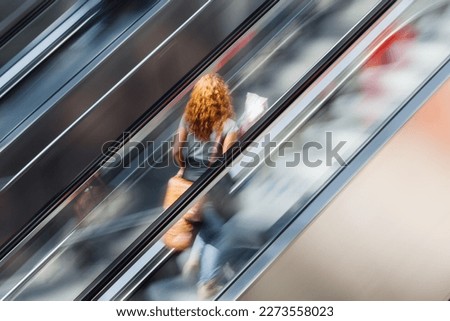 picture of a woman on an escalator with motion blur effect Royalty-Free Stock Photo #2273558023