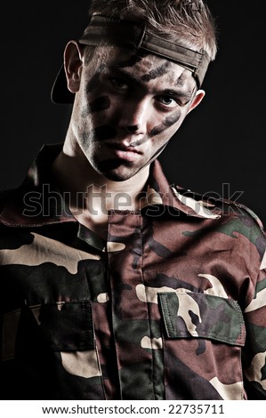 portrait of young serious soldier against black background