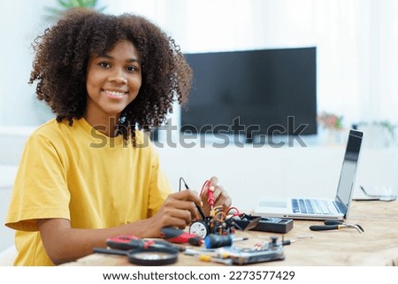 Happy cheerful American - African black ethnicity female university student learning about robotic and programing by herself, woman assemble a robot. Royalty-Free Stock Photo #2273577429