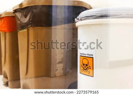 White plastic bin for hazardous waste in hospital.Trash for dangerous garbage from chemotherapy patients.Medical product waste in hospital.An orange sticker that sign of danger garbage.