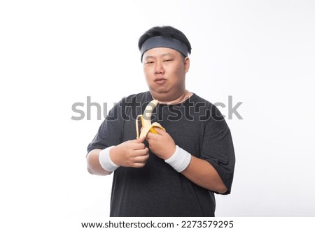 Young Asian funny fat sport man holding banana isolated on white background. Healthy lifestyle concept.