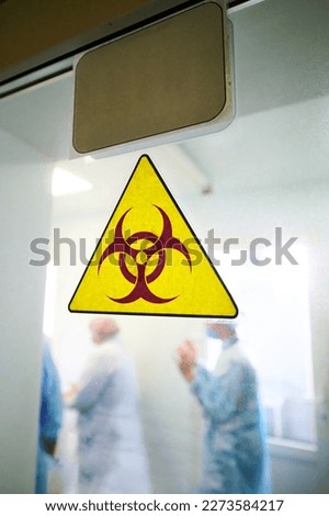 Biohazard warning sign on transparent laboratory door
