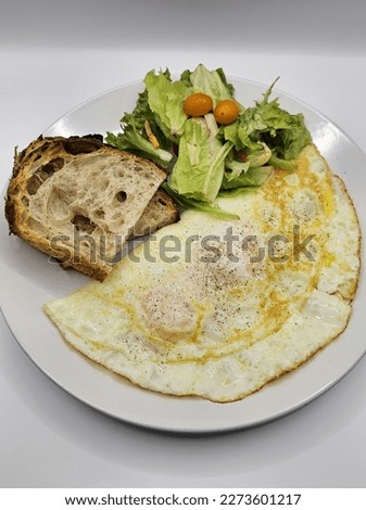 Picture of a plate of slices of sourdough bread, salads and egg for breakfast.